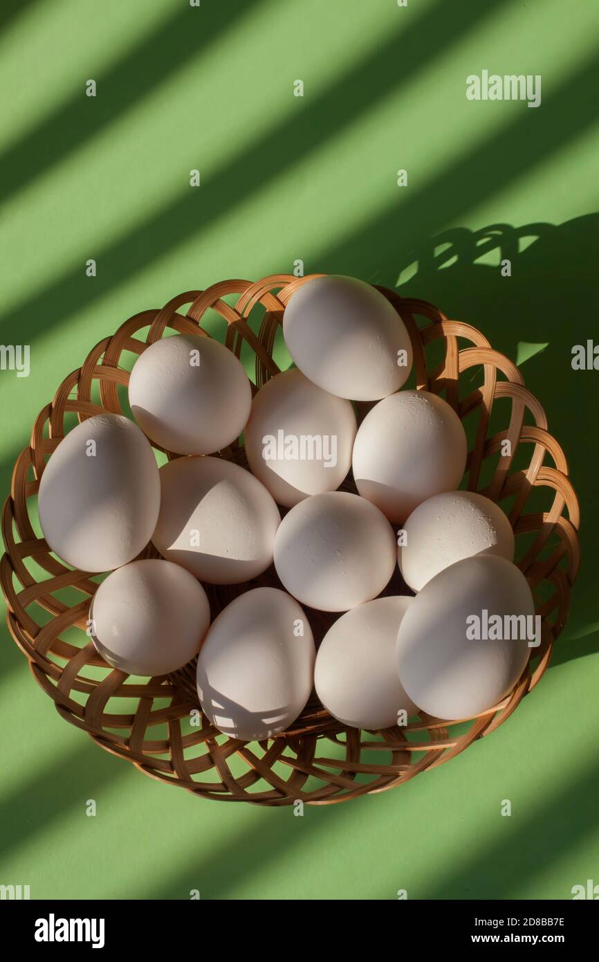 White eggs in basket with green background and copy space Stock Photo