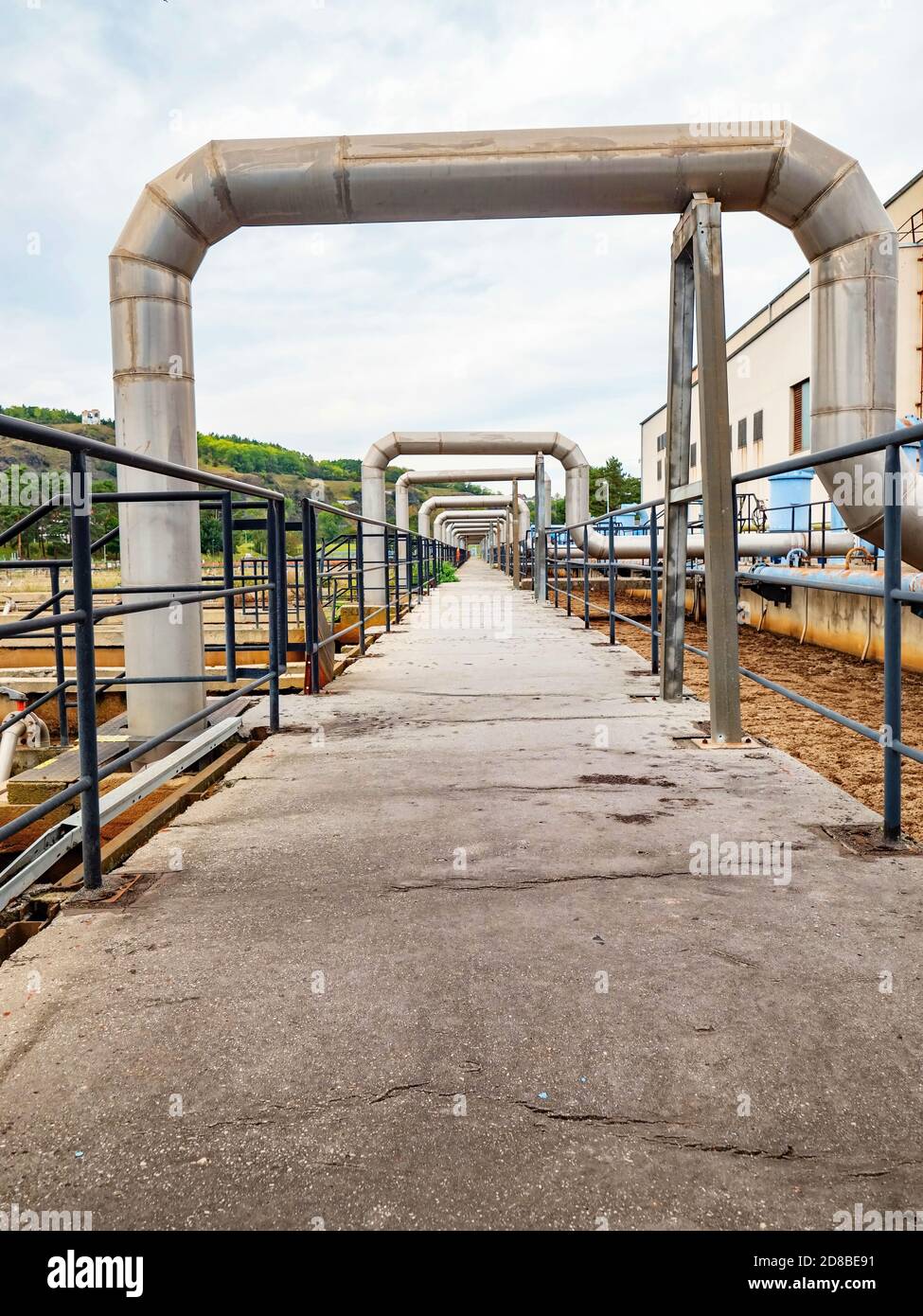 Industrial pipelines in loop on pipe bridge. Tanks field of city wastewater treatment company. Stock Photo