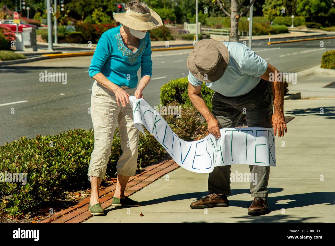 Retired residents wear masks due to the coronavirus pandemic as they unfold a sign at a silent demonstration in favor of the Black Lives Matter moveme Stock Photo