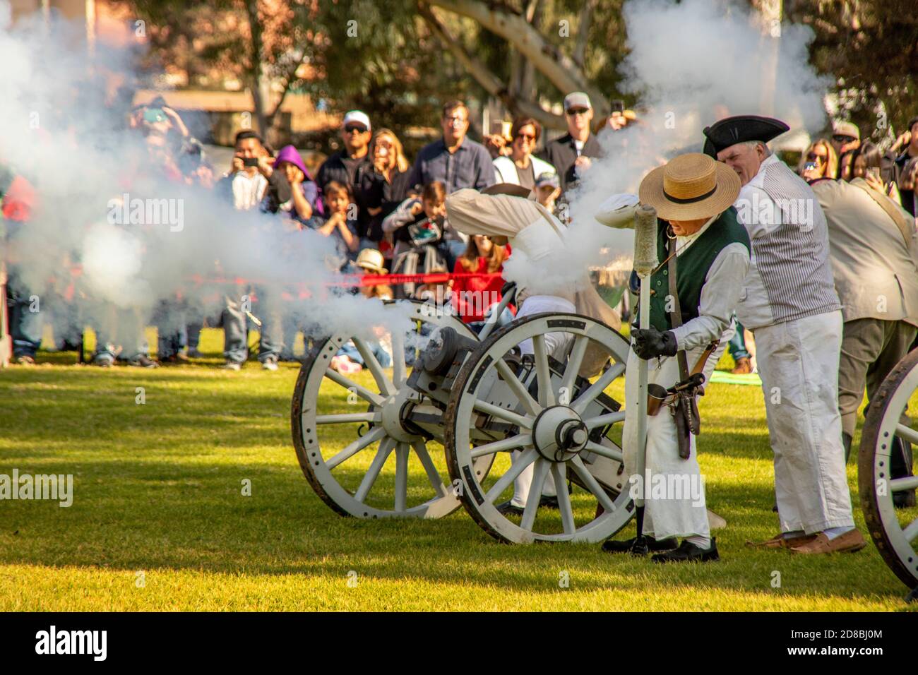 A rebel canon fires as actors portray an artillery crew before an attentive audience at a historical reenactment of an American Revolutionary War batt Stock Photo