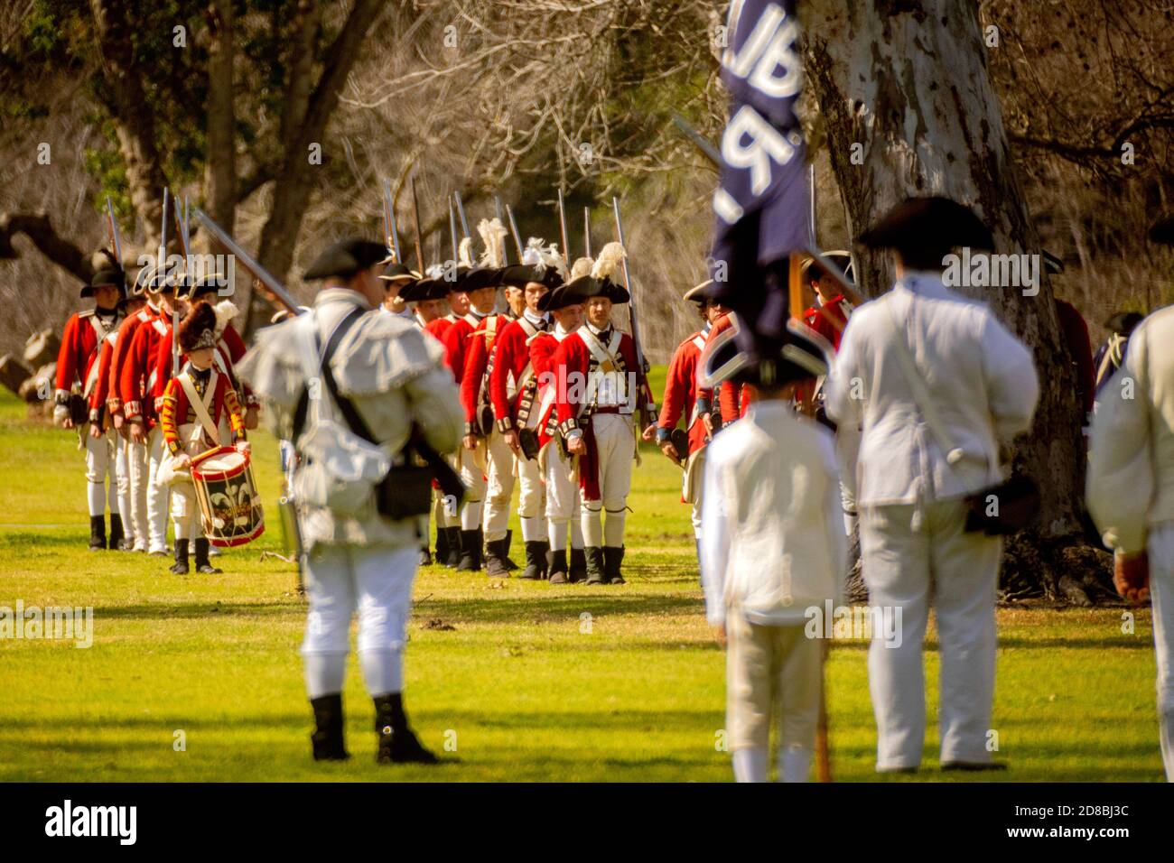 Holding a 'Liberty' flag, actors portraying American rebels confront Redcoats at historical reenactment of an American Revolutionary War in a Huntingt Stock Photo