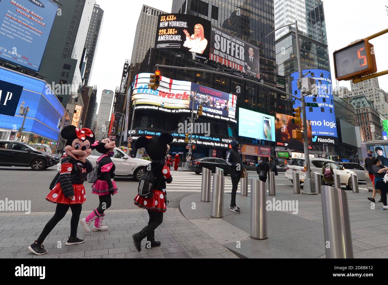 New York City, USA. 28th Oct, 2020. Three women dressed as Disney character Minnie Mouse cross the street at the intersection where two side by side posters featuring Ivanka Trump and her husband Jared Kushner, both senior White House advisors, with messages of indifference regarding COVID-19, on display in Times Square, in New York, NY, October 28, 2020. Created by the Lincoln Project, a conservative anti-Trump organization, has been threatened with a lawsuit by lawyers representing the couple if the billboards are not removed. (Anthony Behar/Sipa USA) Credit: Sipa USA/Alamy Live News Stock Photo