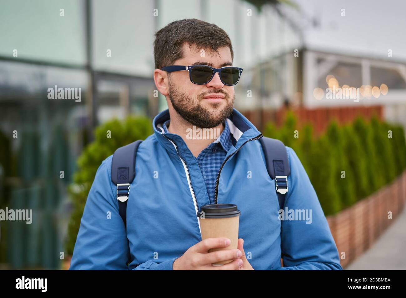 Young man drinks coffee from paper cup outside. Stock Photo