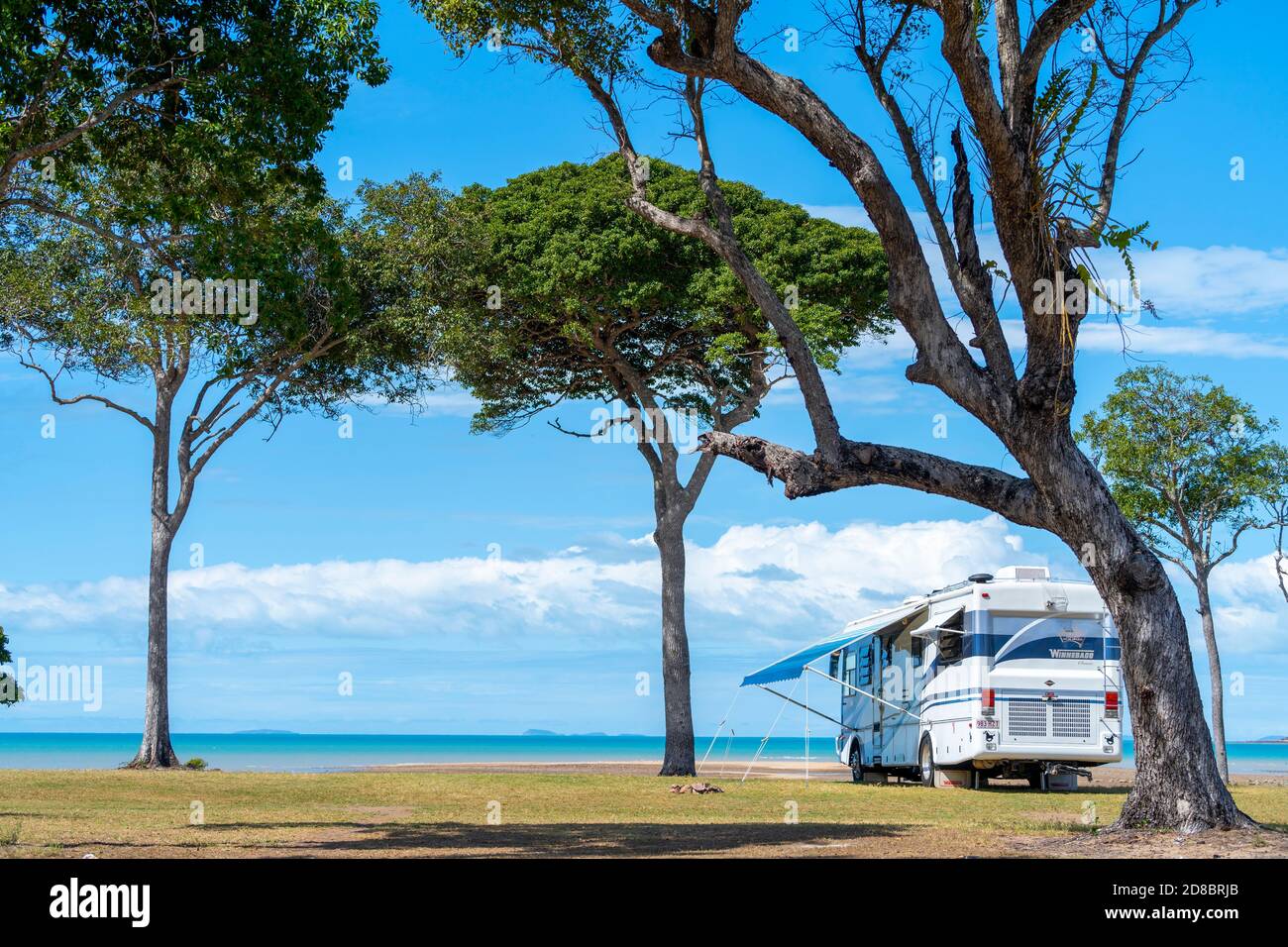 Large motorhome parked under trees on beachfront, Clairview, Central Queensland, Australia Stock Photo