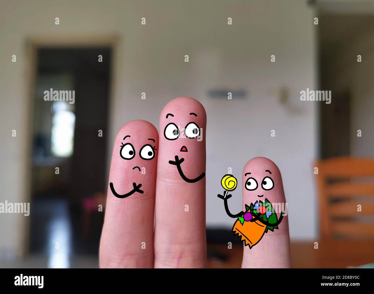 Three fingers are decorated as three person. Parents are not happy that their kid is eating snacks. Stock Photo