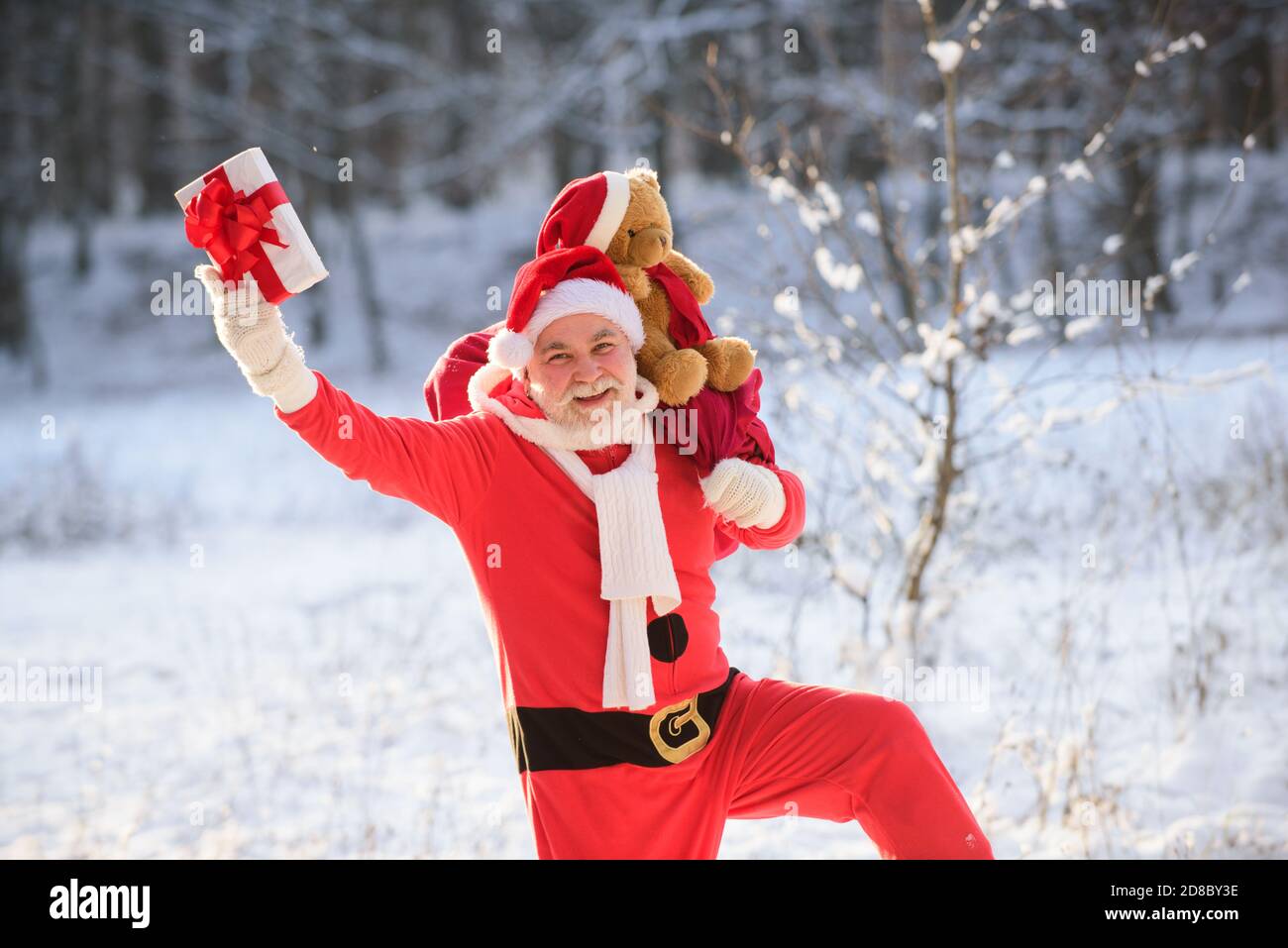 Happy Santa Claus coming to the winter forest with a bag of gifts, snow ...