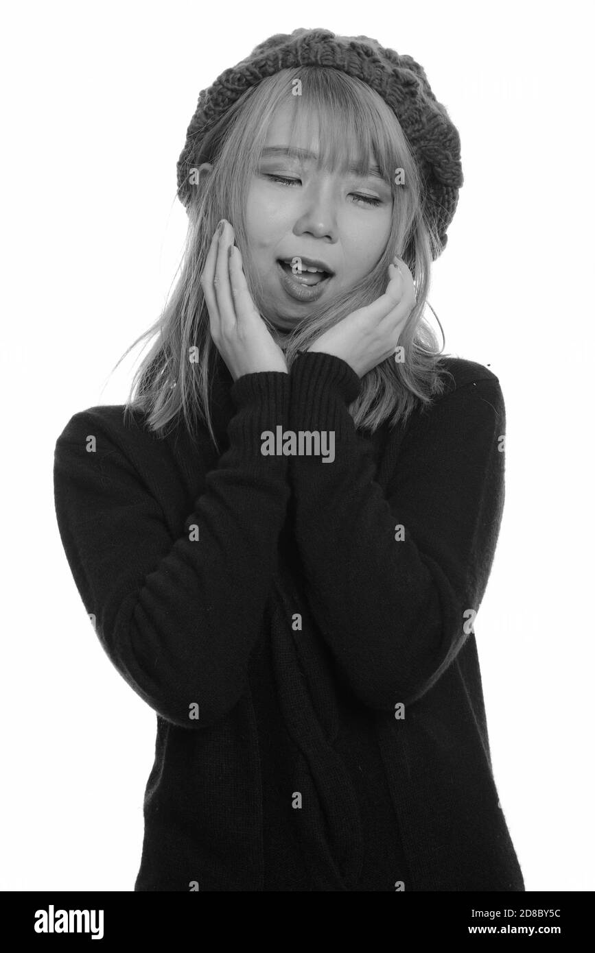 Young happy Asian woman smiling with closed eyes while touching her face Stock Photo