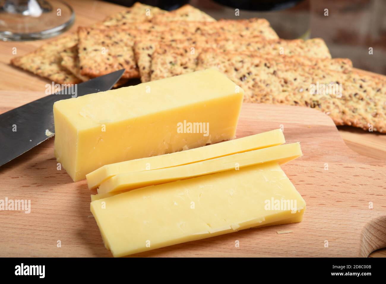 Sliced white cheddar cheese on a cutting board Stock Photo