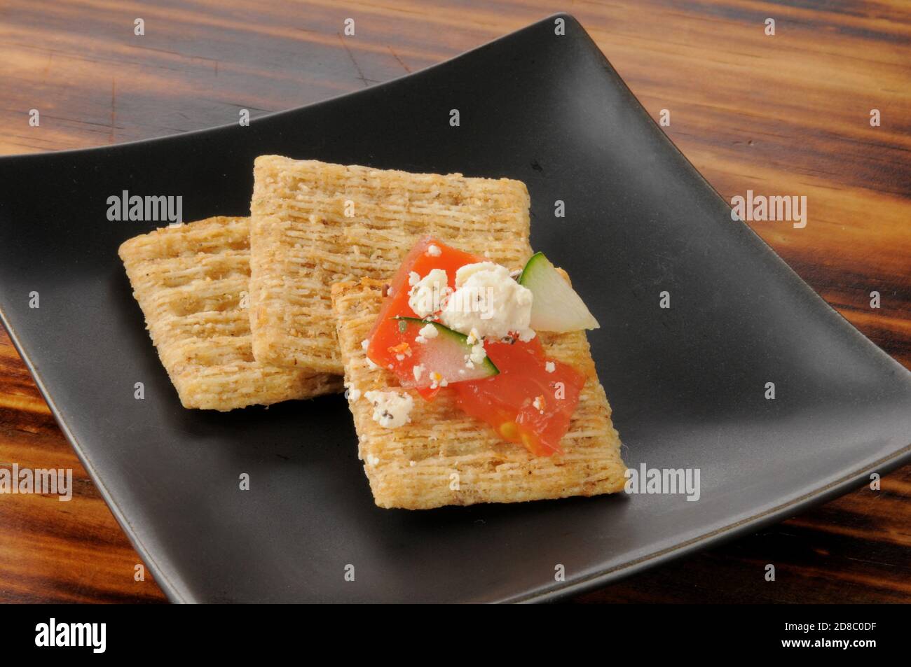 Healthy whole wheat crackers with tomato, cucumber and feta cheese