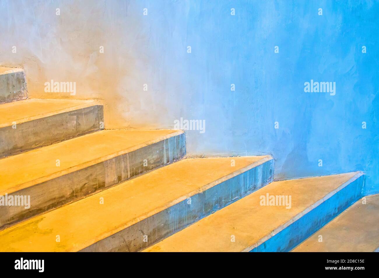 Concrete stairs around a round building with a color gradient from warm yellow to cold blue Stock Photo
