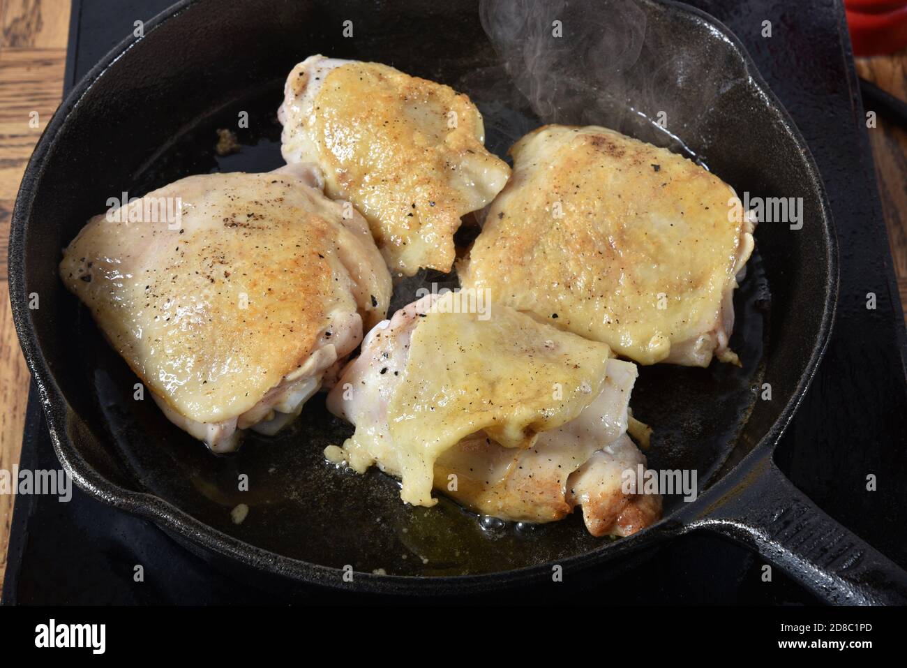 Chicken thighs frying in a cast iron skillet Stock Photo Alamy