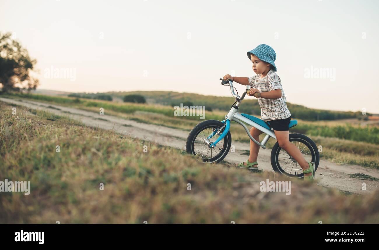 Side view photo of a caucasian boy with blue hat riding a bike on a ...