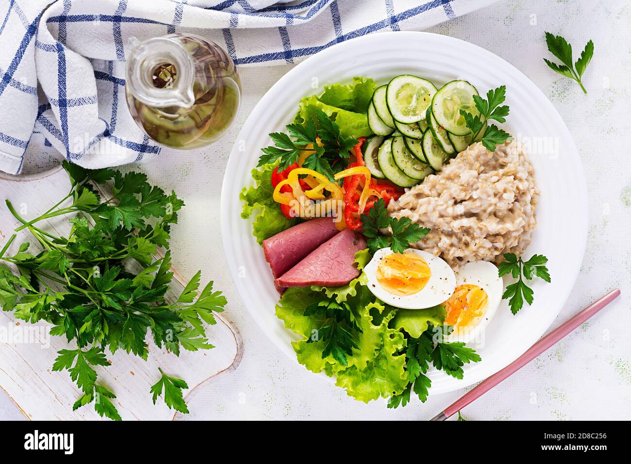 Breakfast oatmeal porridge with boiled egg, ham and vegetables salad