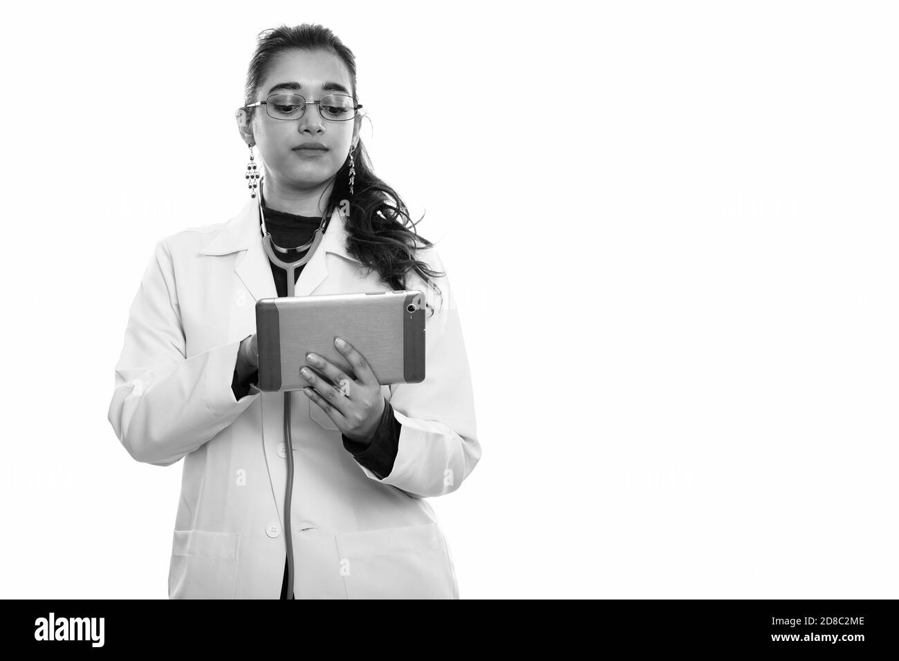 Studio shot of young beautiful Indian woman doctor using digital tablet Stock Photo