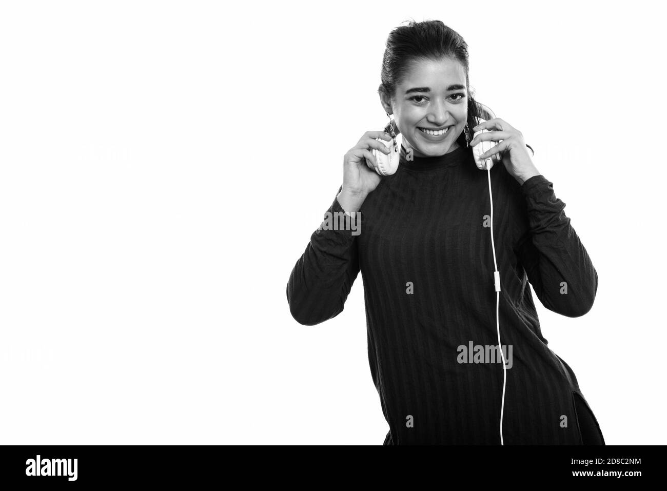 Young happy Indian woman smiling while holding headphones Stock Photo