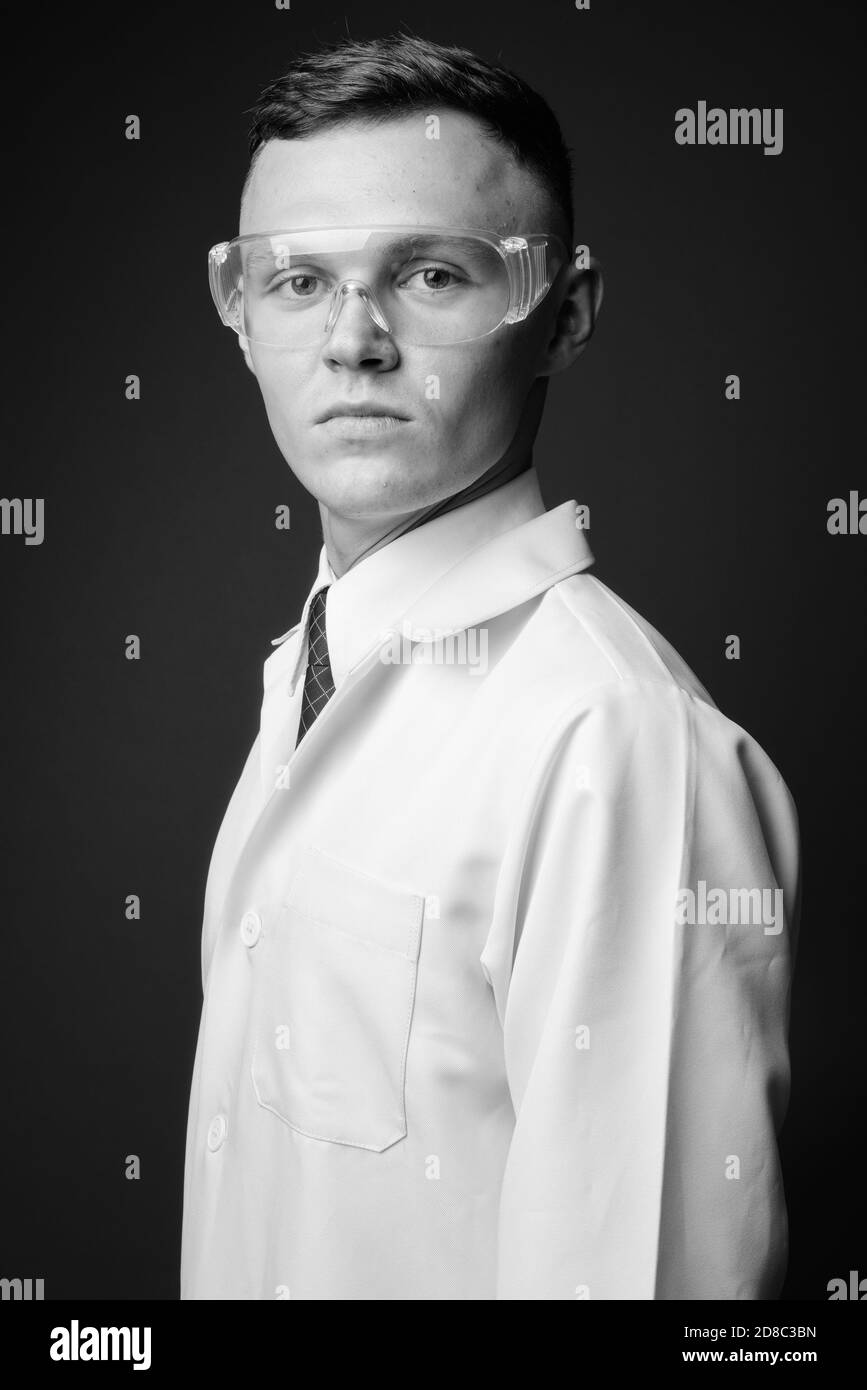 Young man doctor wearing protective glasses against gray background Stock Photo
