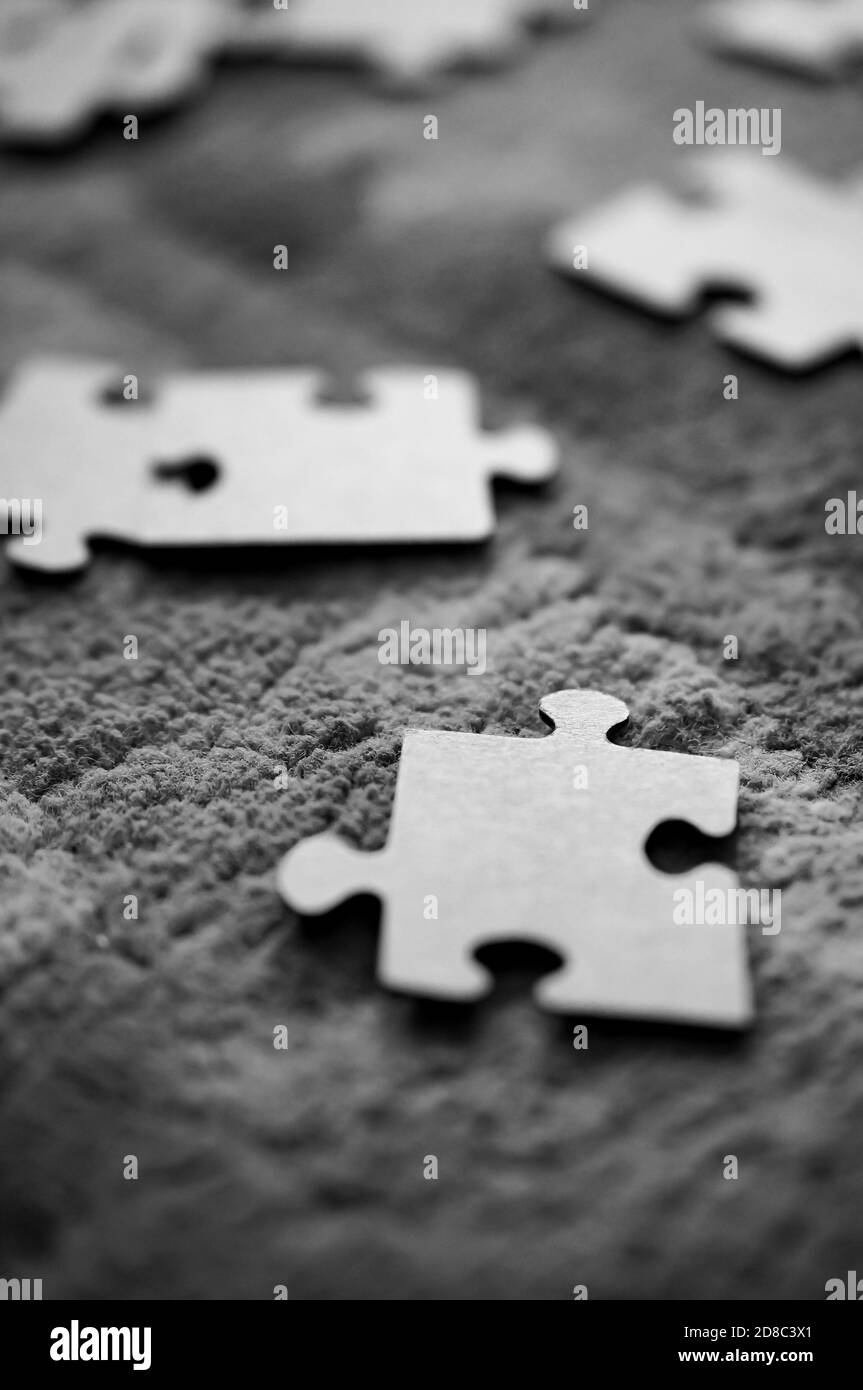 Greyscale closeup of grey puzzle pieces placed on a fluffy carpet Stock