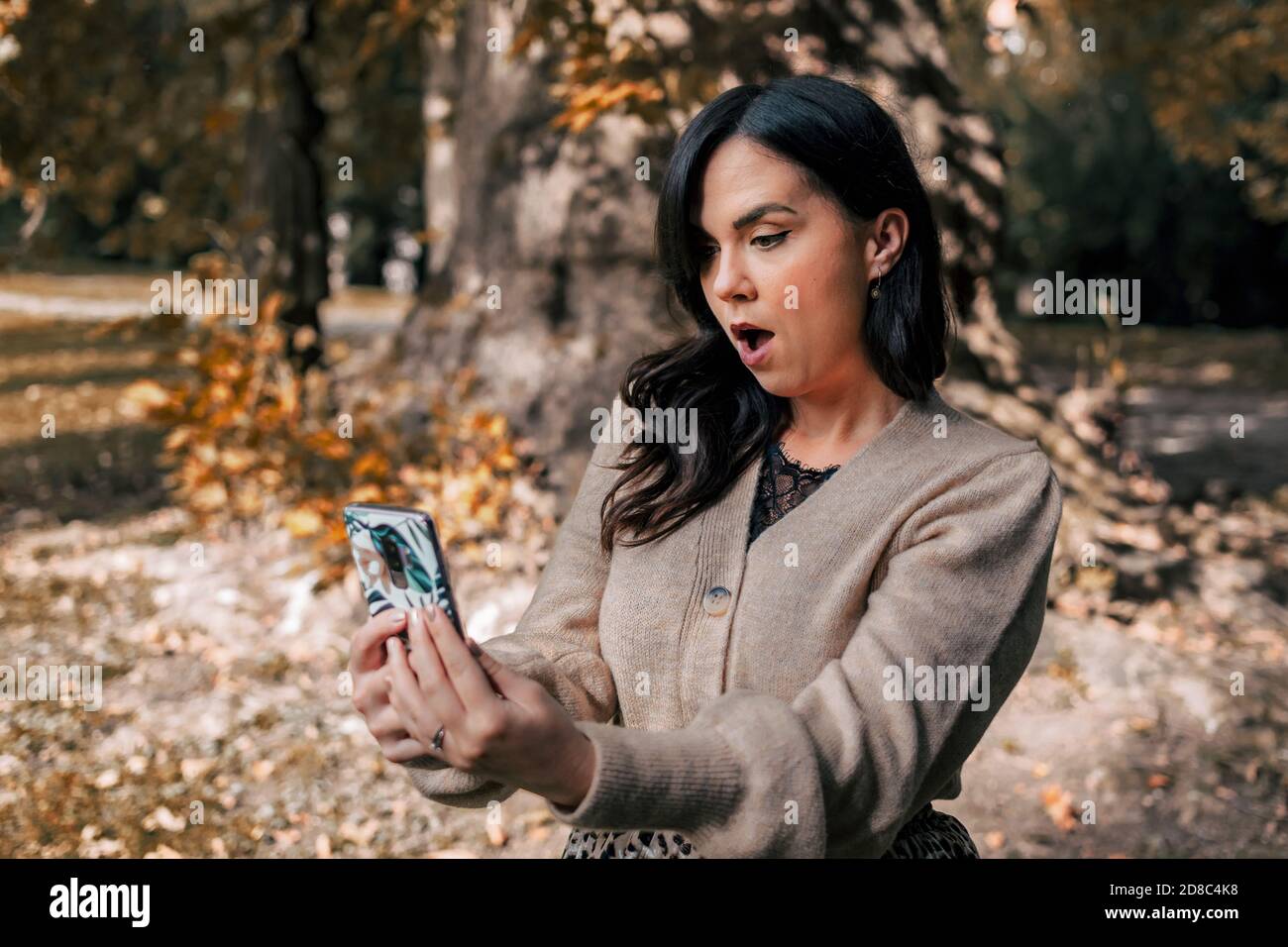 Female looking at her phone with a shocked face expression Stock Photo