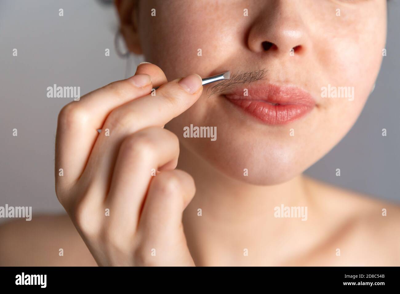A young woman plucks her hair over her upper lip with tweezers. The concept of getting rid of unwanted facial hair Stock Photo - Alamy A young woman plucks her hair over her upper lip with tweezers. The concept of getting rid of unwanted facial hair Stock Photo - Alamy