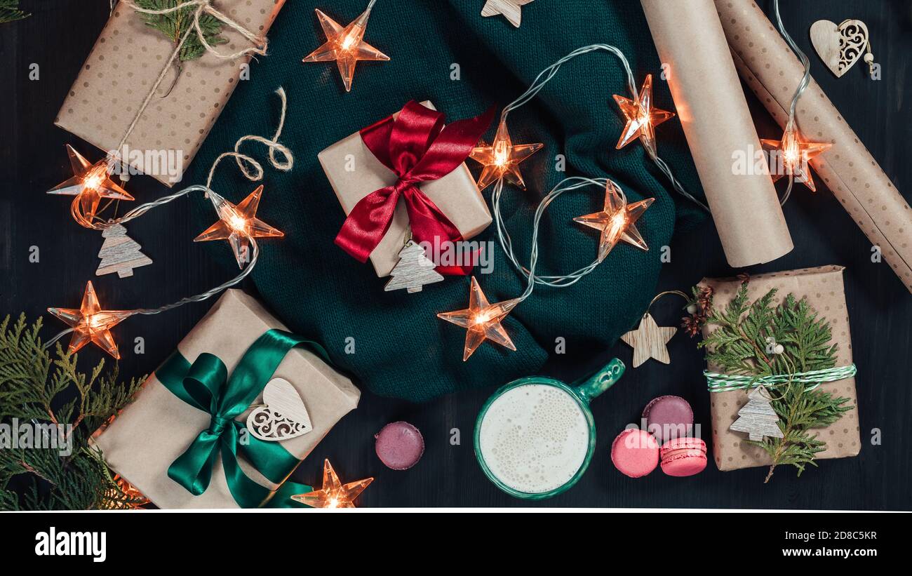 Christmas flat lay with craft gift boxes, garland lights and decorations on dark wooden background Stock Photo