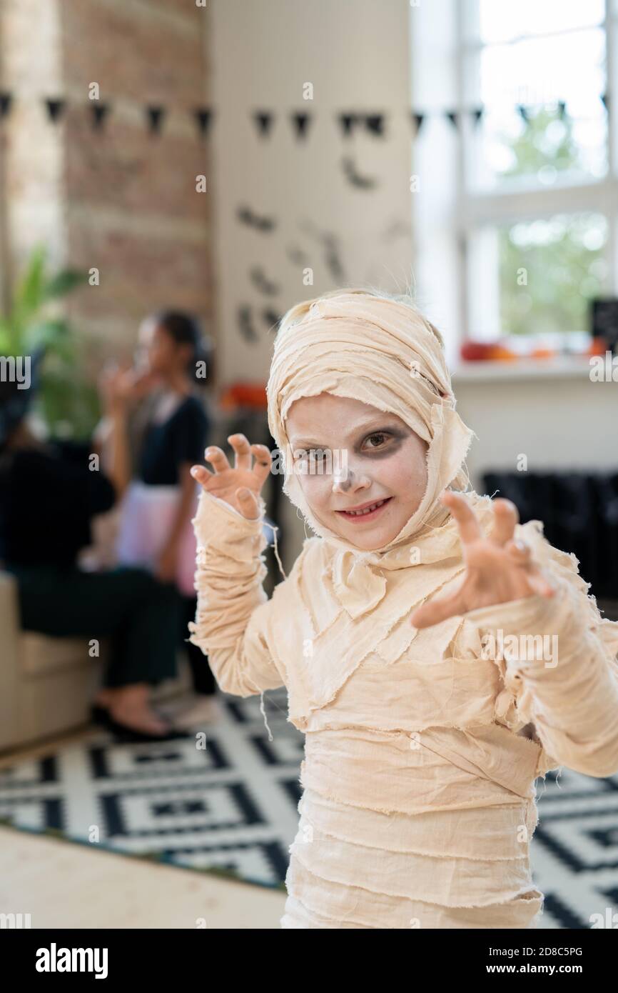 Portrait of charismatic mummy boy in bandages making boo gesture while having fun at Halloween party Stock Photo