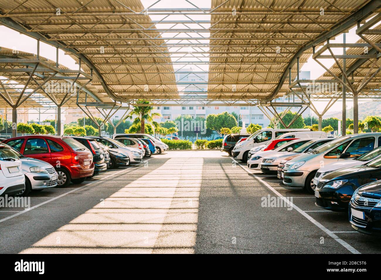 Cars On A Street Parking Lot Under Cover In Sunny Summer Day Stock Photo