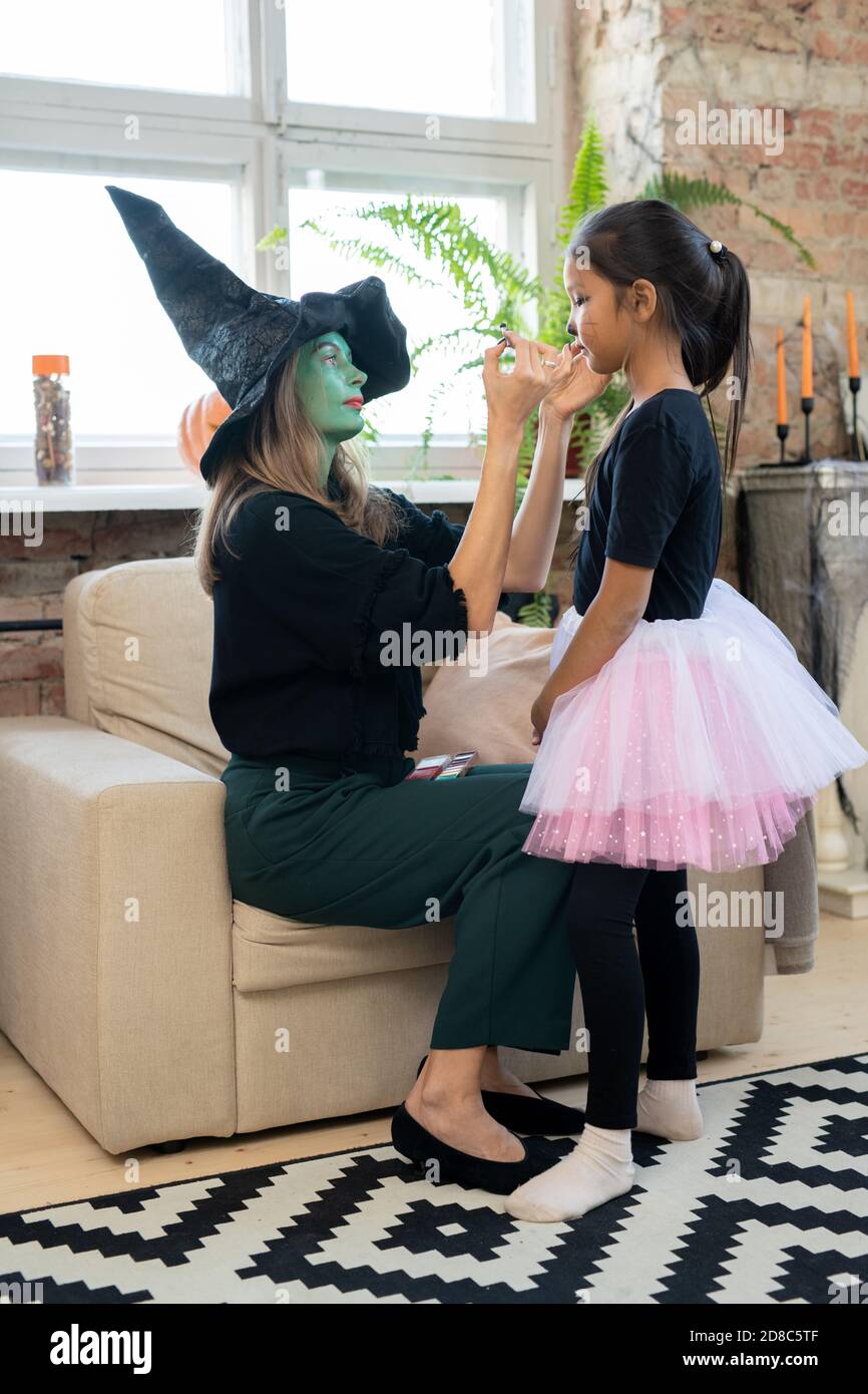 Female Artist with green face wearing witches hat making Halloween ...