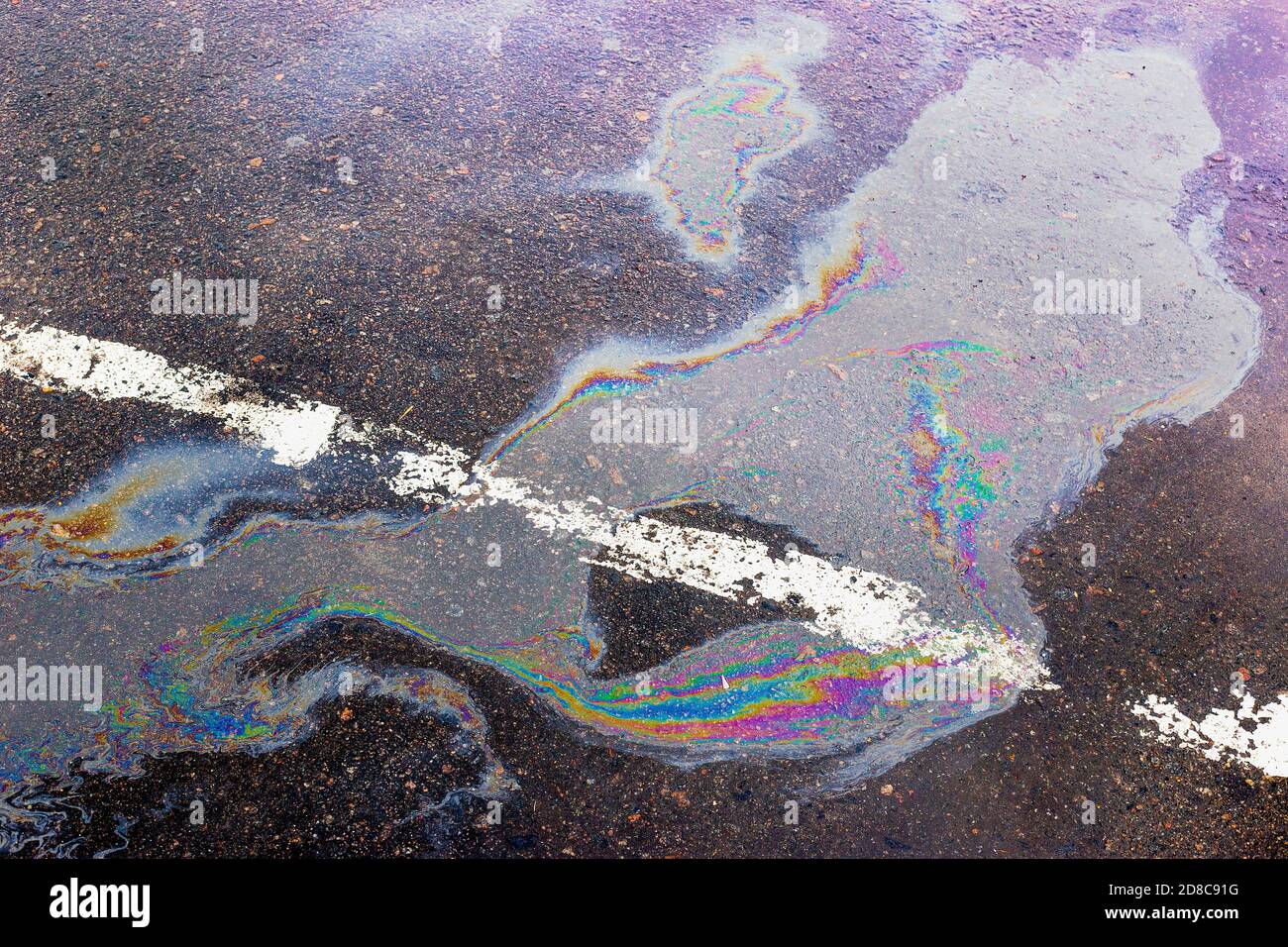 Colorful gas stain on wet asphalt. Oil stain caused by a leak under a