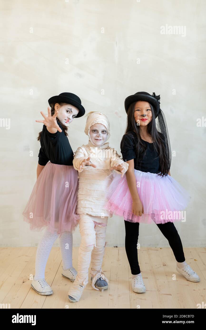 Portrait of smiling charismatic interracial children in cool Halloween costumes standing together and posing for group photo at party Stock Photo