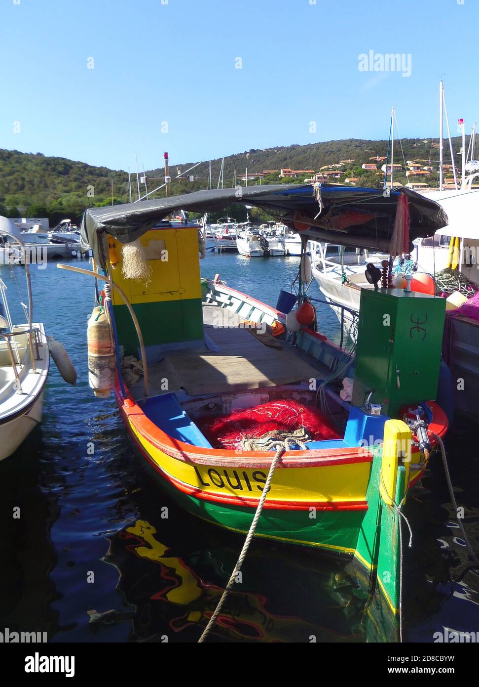 Brightly painted fishing boats anchored in the harbour of sleepy seaside village   Porto Pollo, Gulf of Valinco, Corsica France Stock Photo