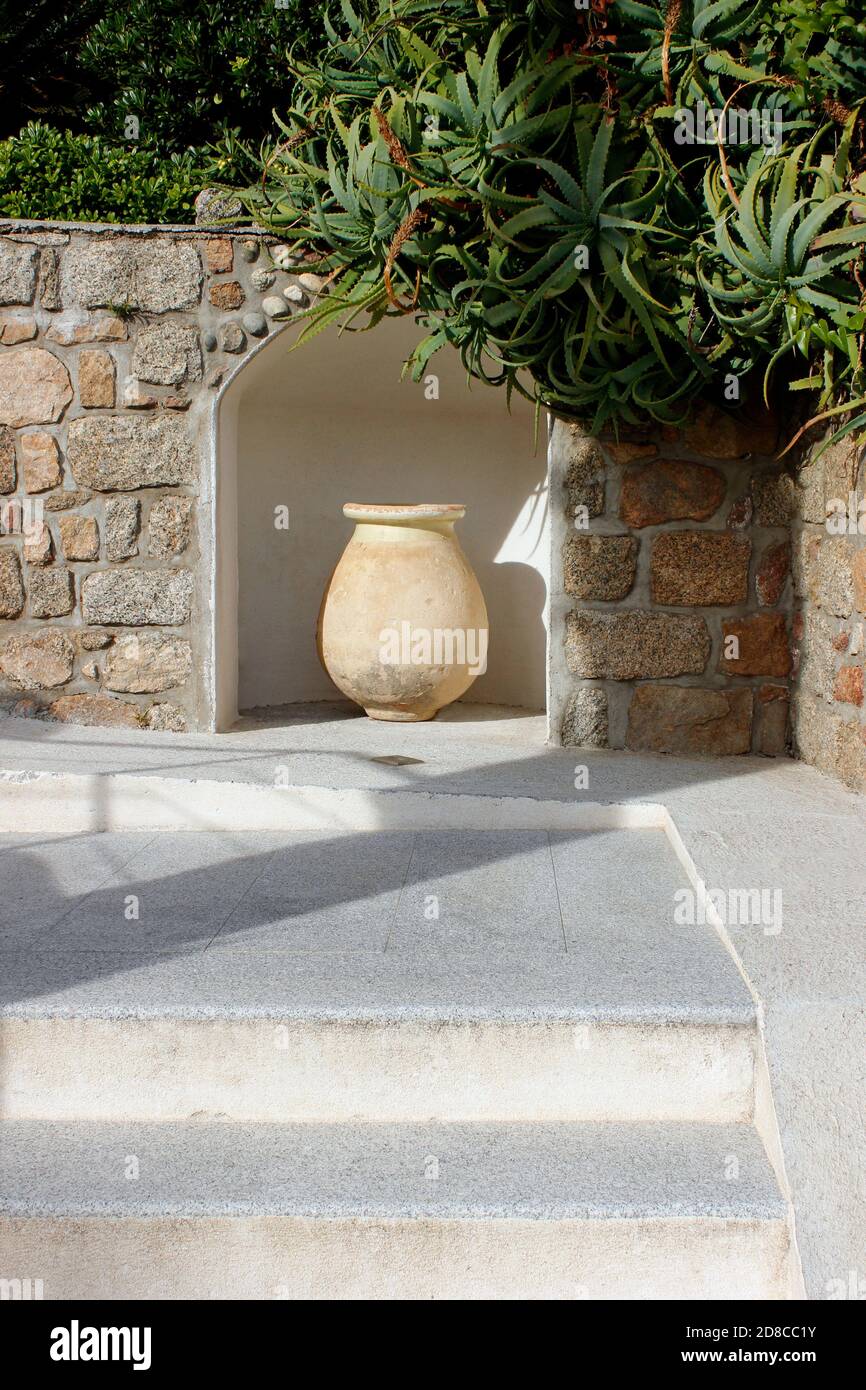 Solitary large ornamental terracotta pot artistically displayed in a garden alcove Stock Photo