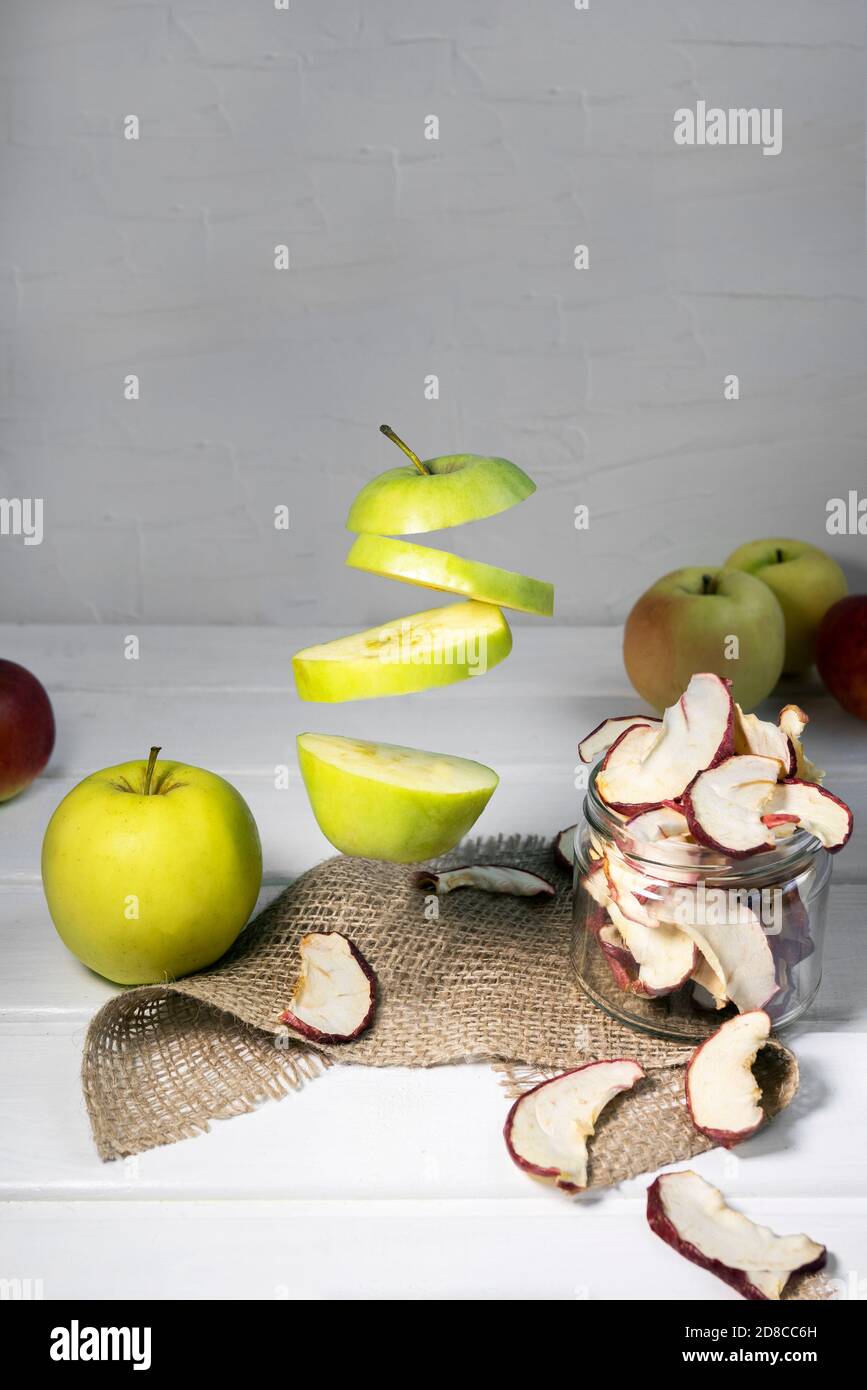Dried Dehydrated Apple Chips in Glass Jar with Fresh Sliced Apple on white background, Levitation Food Stock Photo