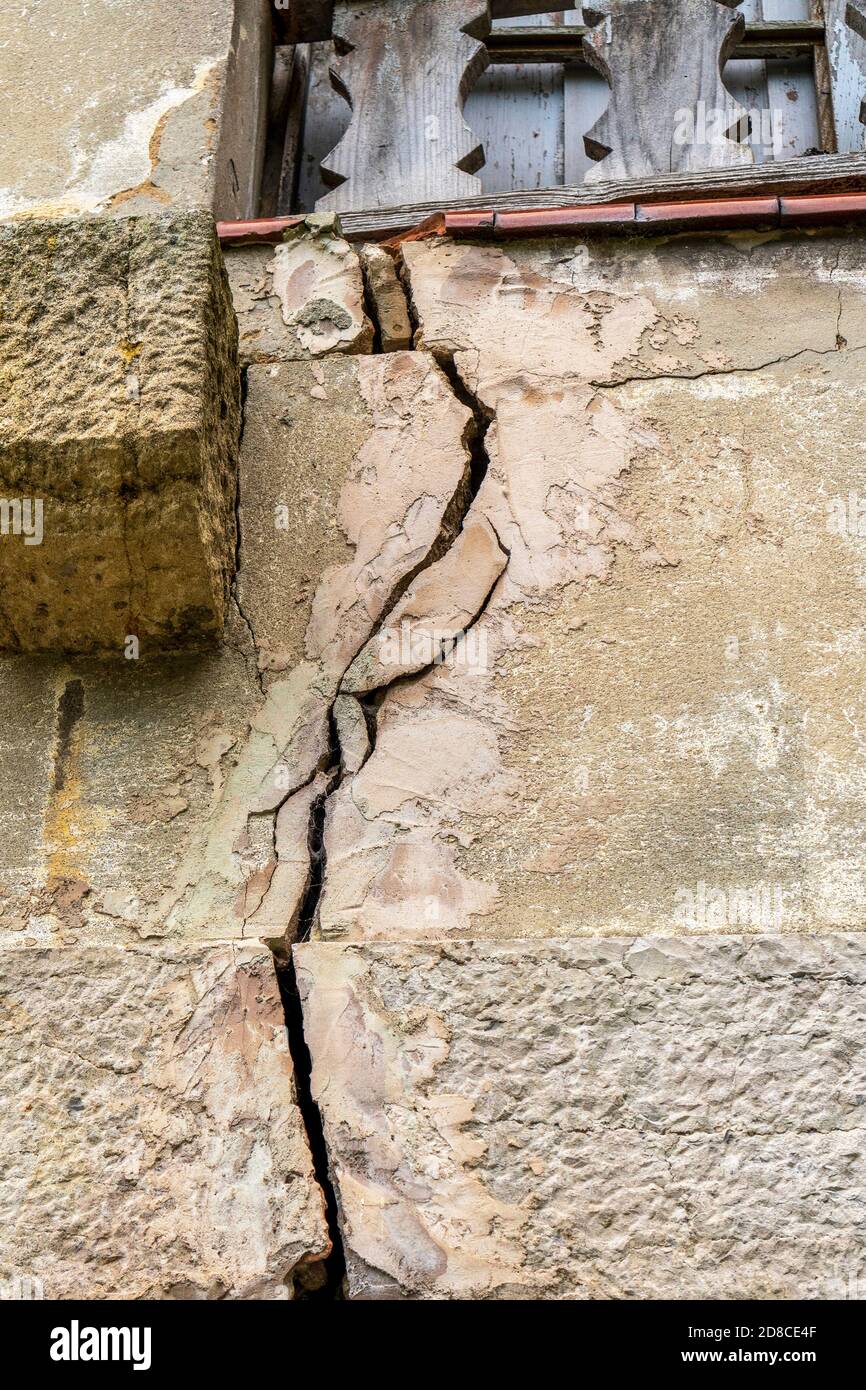destroyed wall of the building close up. Cracks and fractures under a wooden window. The concept of the consequences of wars and armed conflicts Stock Photo