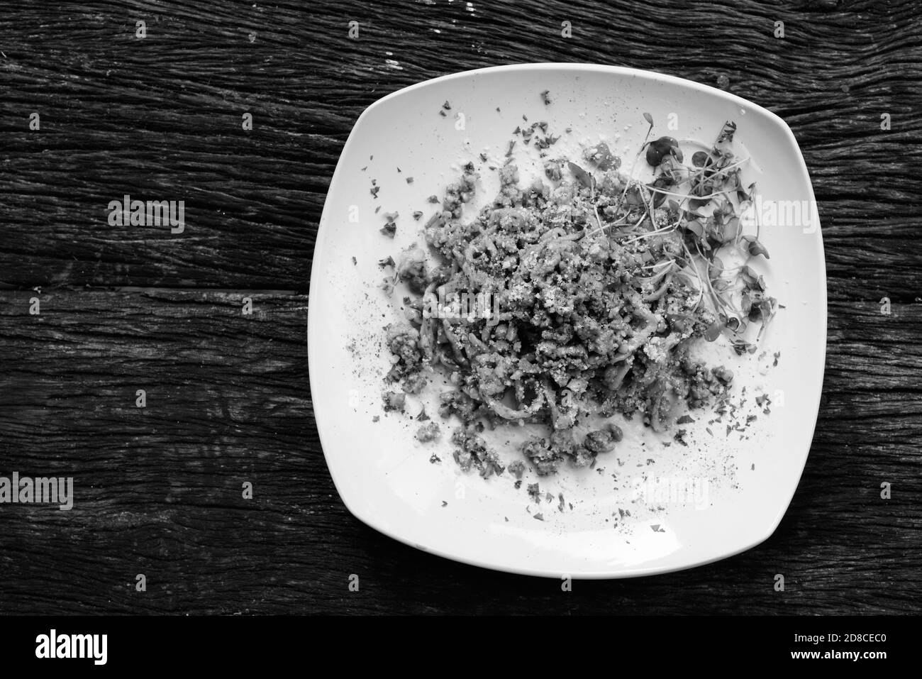 Tagliolini Pasta With Pesto and Sausage Against Wooden Table Stock Photo