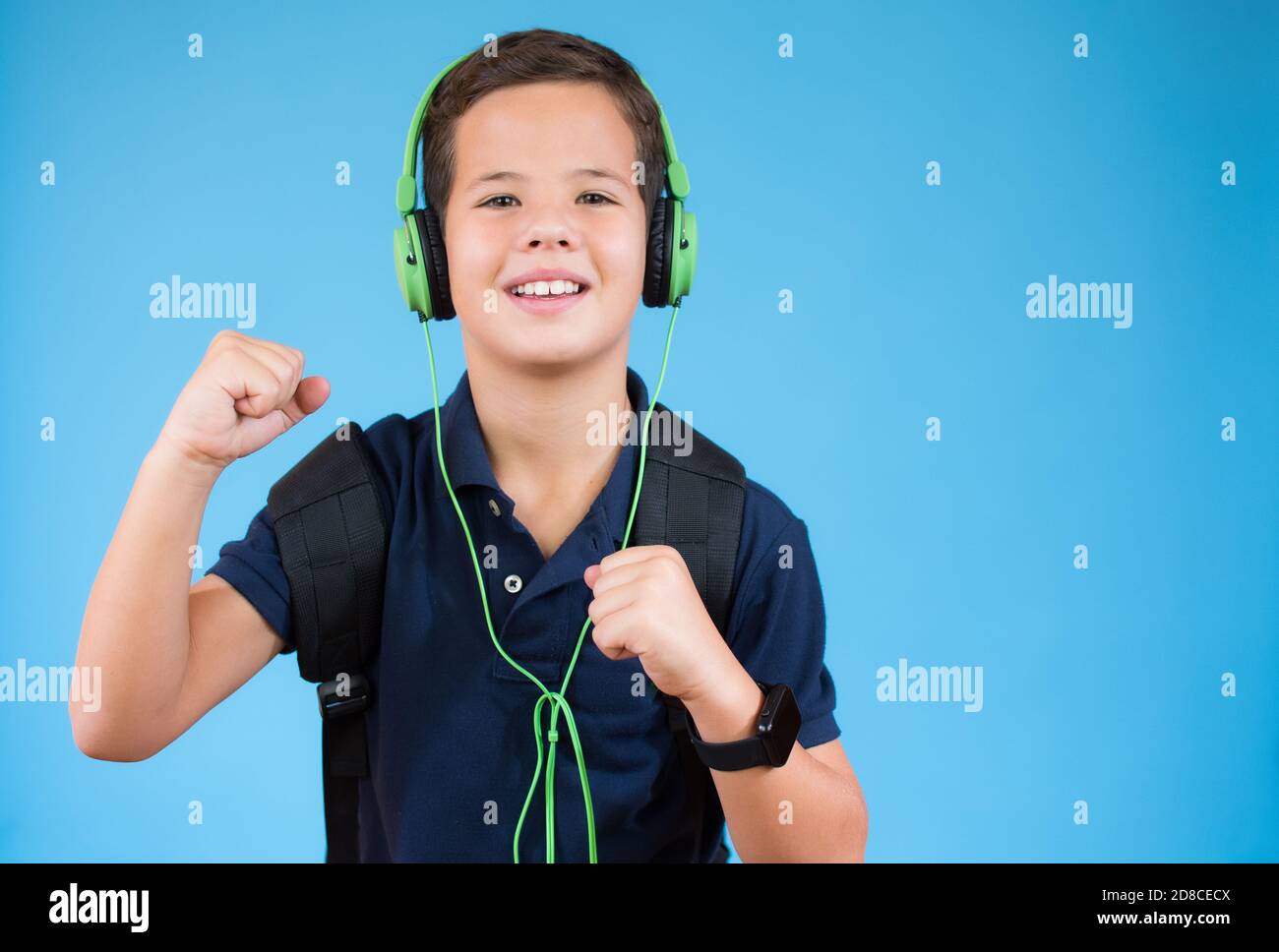 Handsome schoolboy listening to music over blue background Stock Photo ...