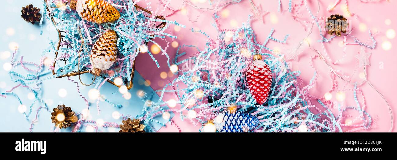 Christmas web-banner. Colored cones in a gift boxes. Christmas lights. Blue-pink background. Flat lay, top view. Stock Photo