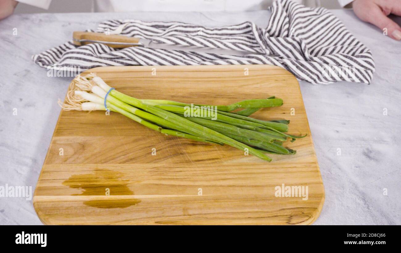 Step by step. Chopping organic green onions on a wood cutting board ...