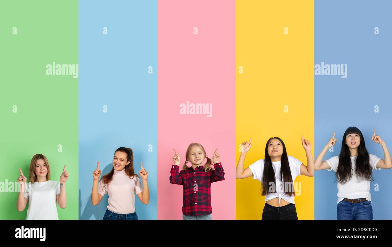 Young people look happy, pointing up on multicolored background. Human emotions, facial expression, sales concept. Trendy colors. Creative collage with copyspace for ad. Beautiful female models. Stock Photo