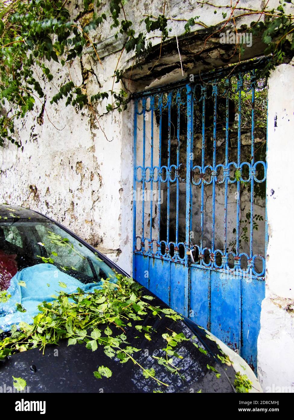 Old Doors on the entrance of a house and leaves on Parked car after heavy rain and wind, Galatas Village, Crete, Greece Stock Photo