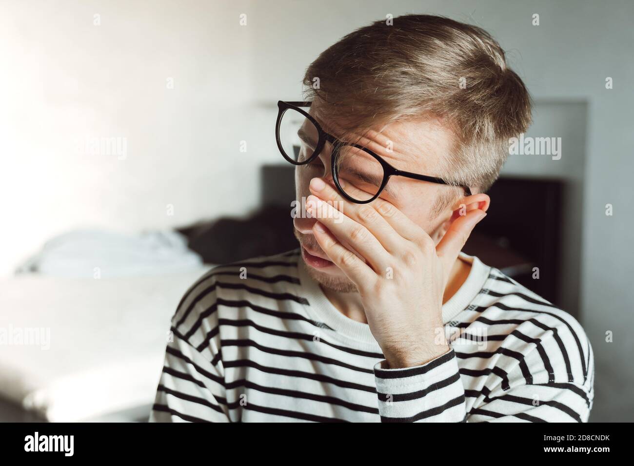 Tired exhausted man taking off glasses, feeling eye strain after work