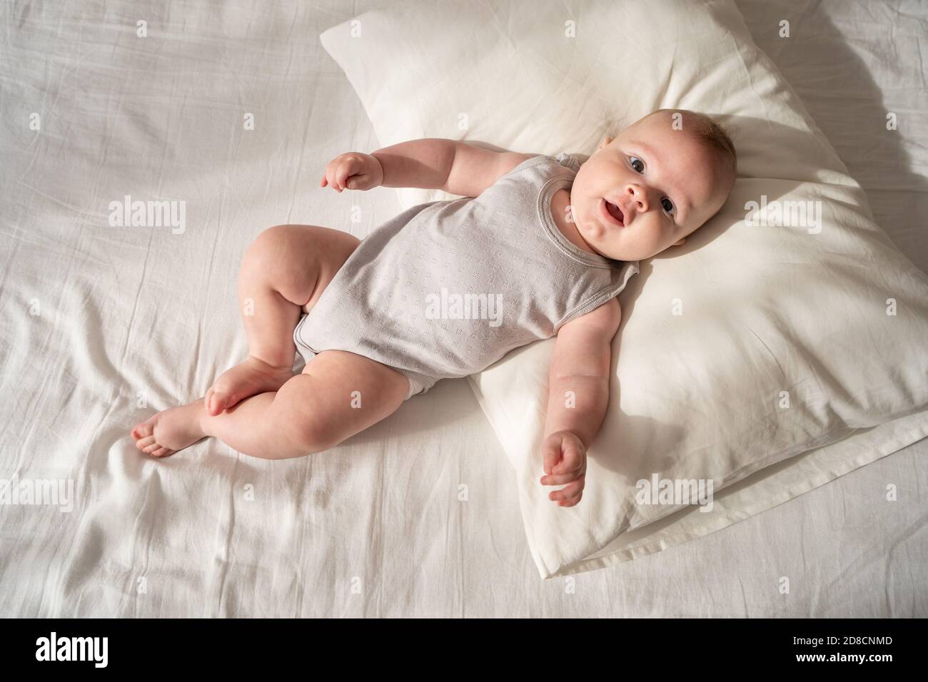 Three month old baby lies on a white bed on a pillow Stock Photo Alamy