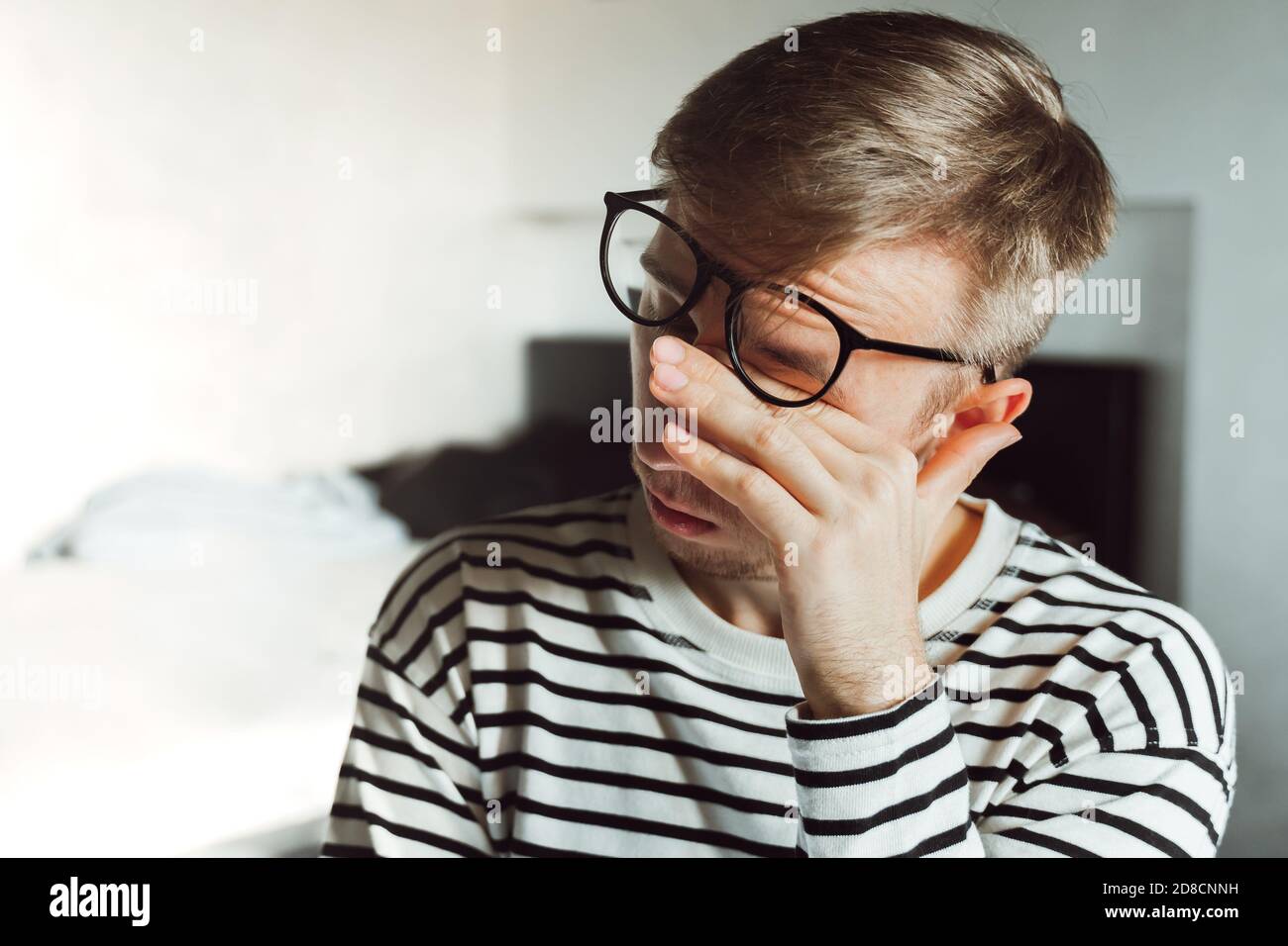 Young man in eyeglasses feeling exhausted, looking tired after reading