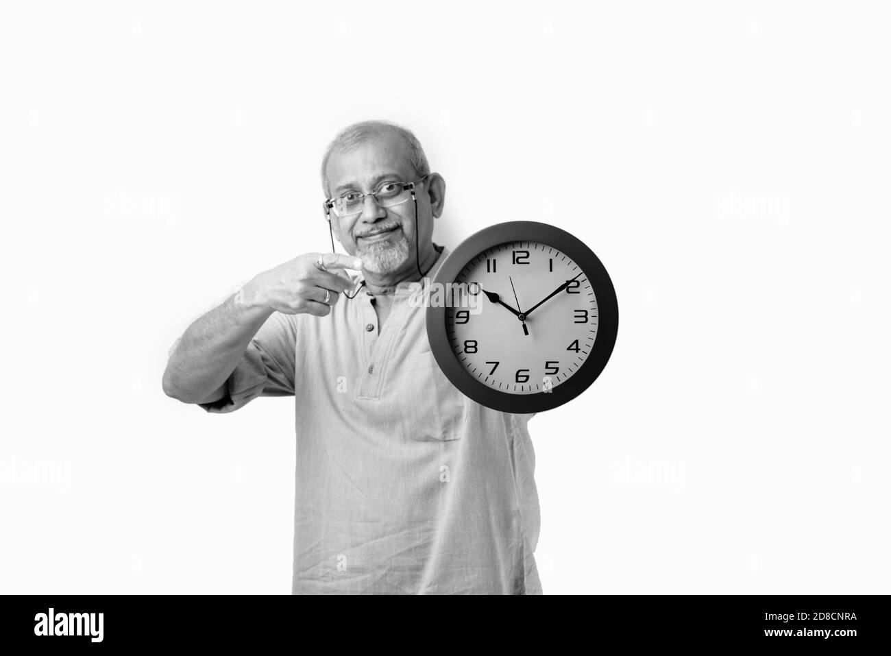 Senior Asian Indian man holding round wall clock - time management concept Stock Photo