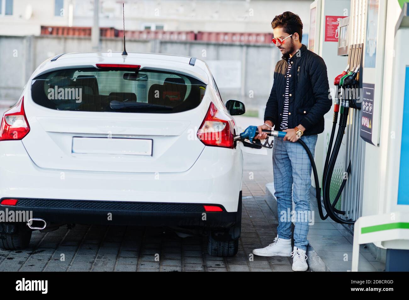 South asian man or indian male refueling his white car on gas station. Stock Photo