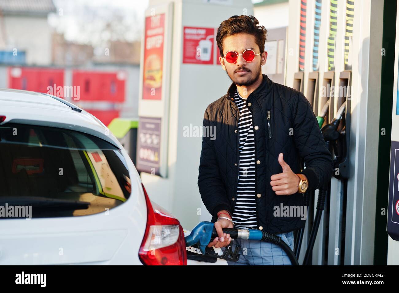 South asian man or indian male refueling his white car on gas station. Stock Photo