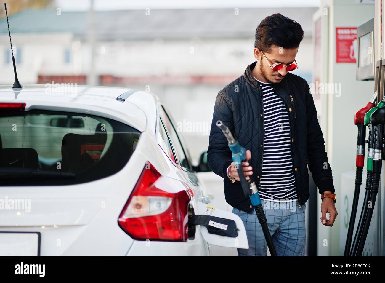 South asian man or indian male refueling his white car on gas station. Stock Photo