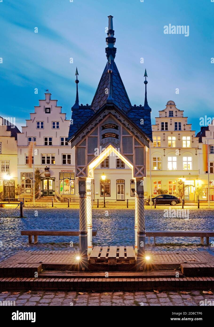 historic water pump on the market square in front of houses with stepped gables in the evening, Germany, Schleswig-Holstein, Northern Frisia, Stock Photo