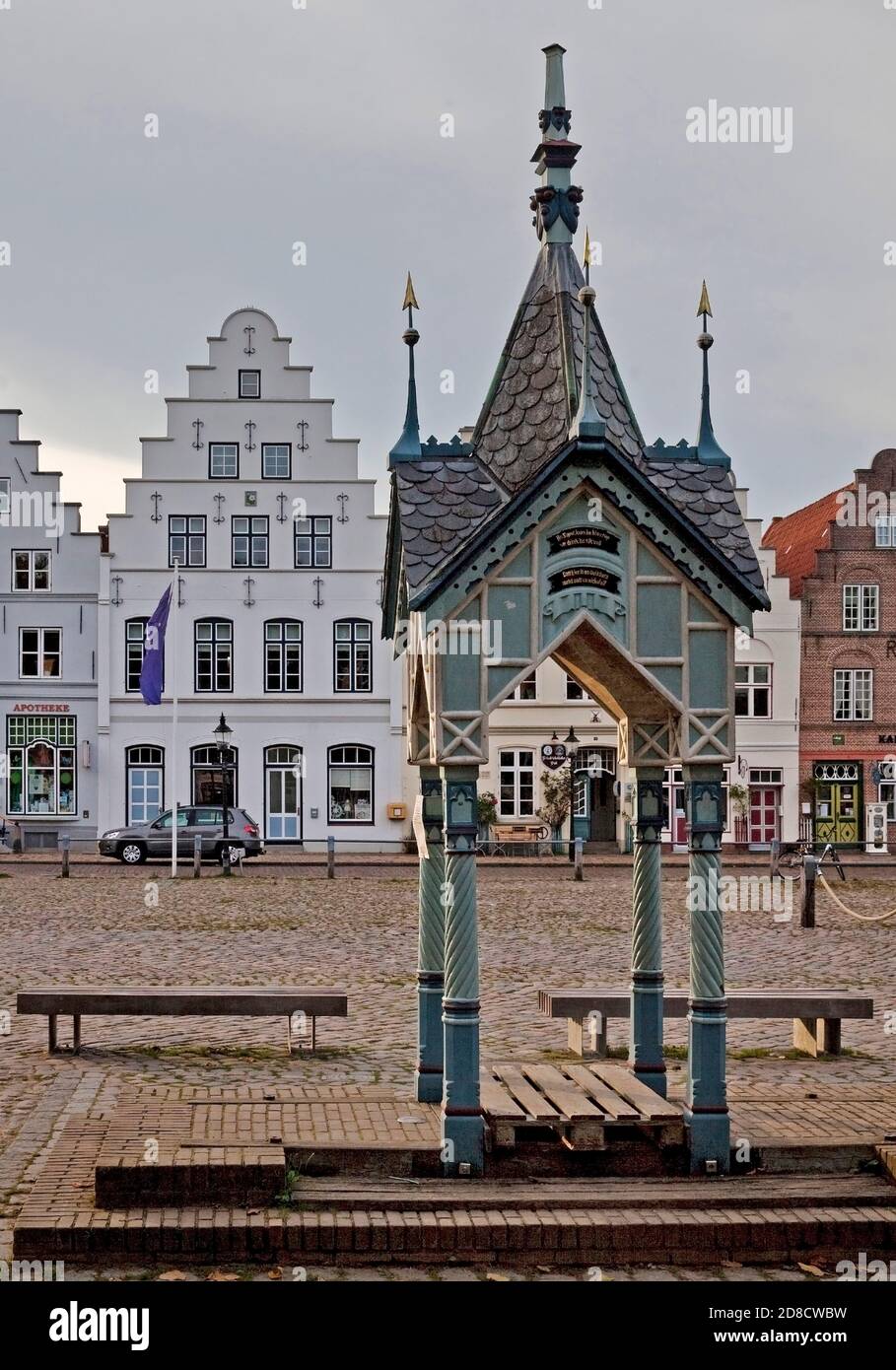 historic water pump on the market square in front of houses with stepped gables, Germany, Schleswig-Holstein, Northern Frisia, Friedrichstadt Stock Photo