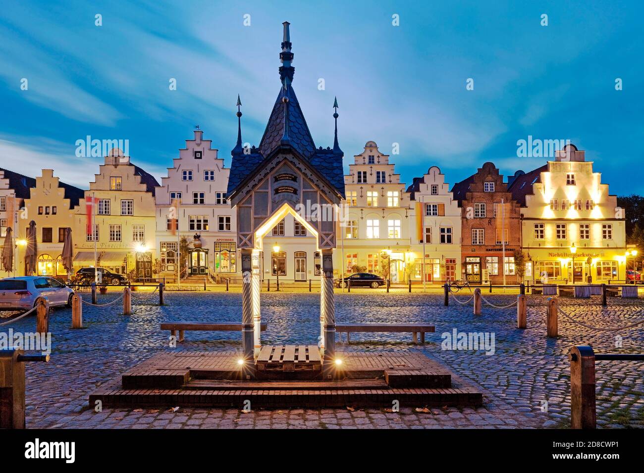 historic water pump on the market square in front of houses with stepped gables in the evening, Germany, Schleswig-Holstein, Northern Frisia, Stock Photo