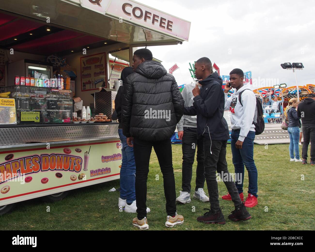 Male teenagers at a coffee stall at a fairground Stock Photo